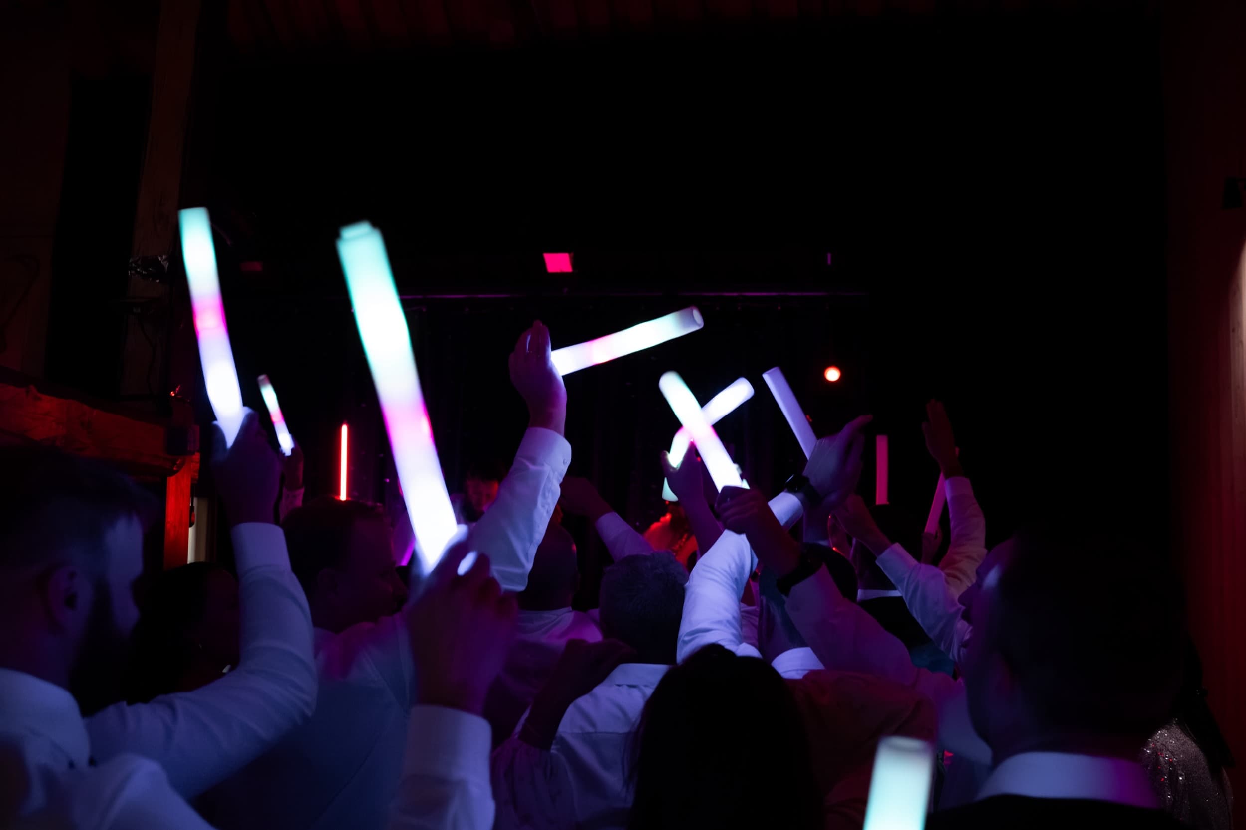 Gjester på dansegulvet løfter lysende glowsticks i mørket