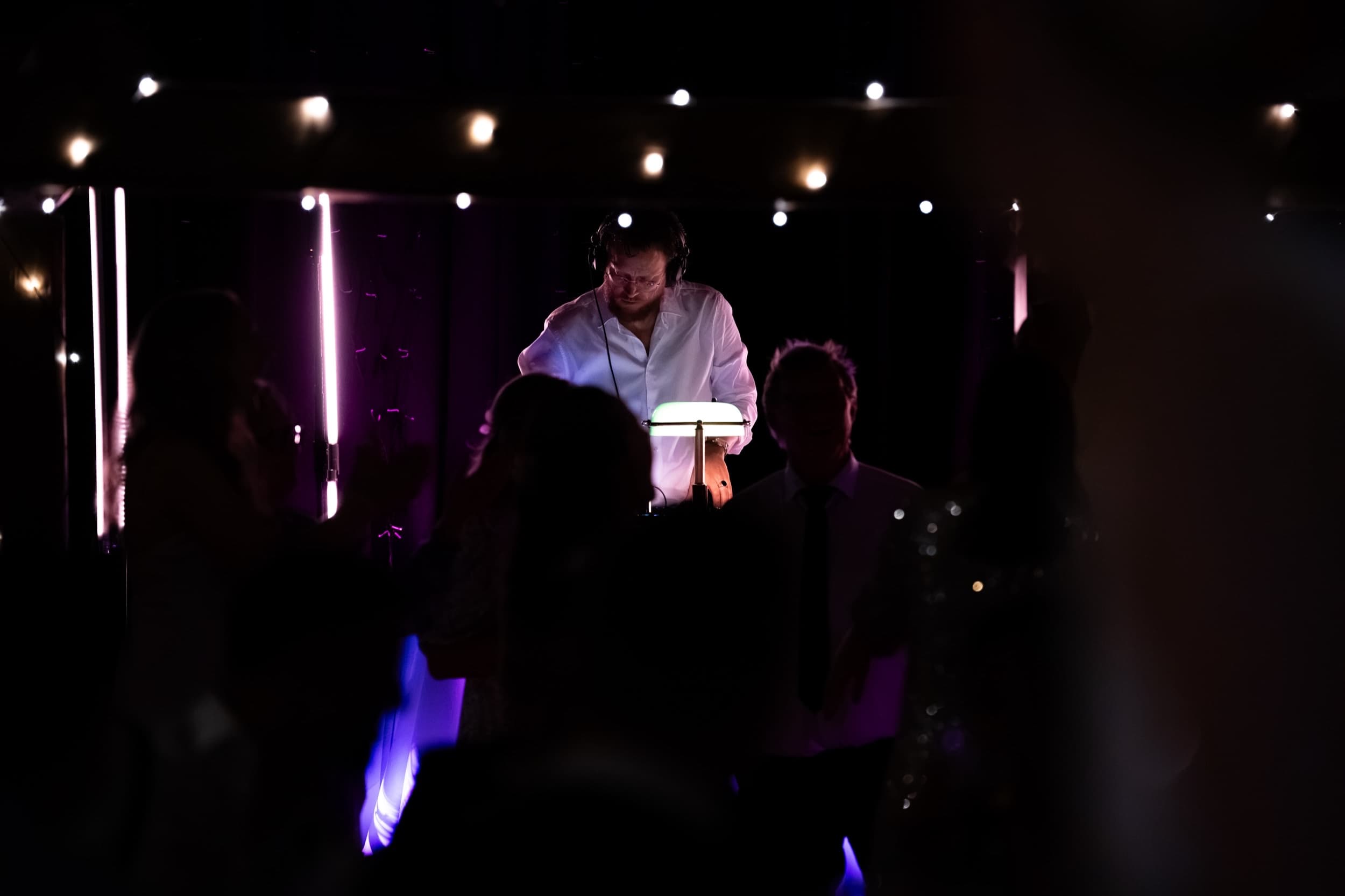 DJ i Trondheim ved miksepulten i et opplyst lokale, fotografert i lilla scenelys