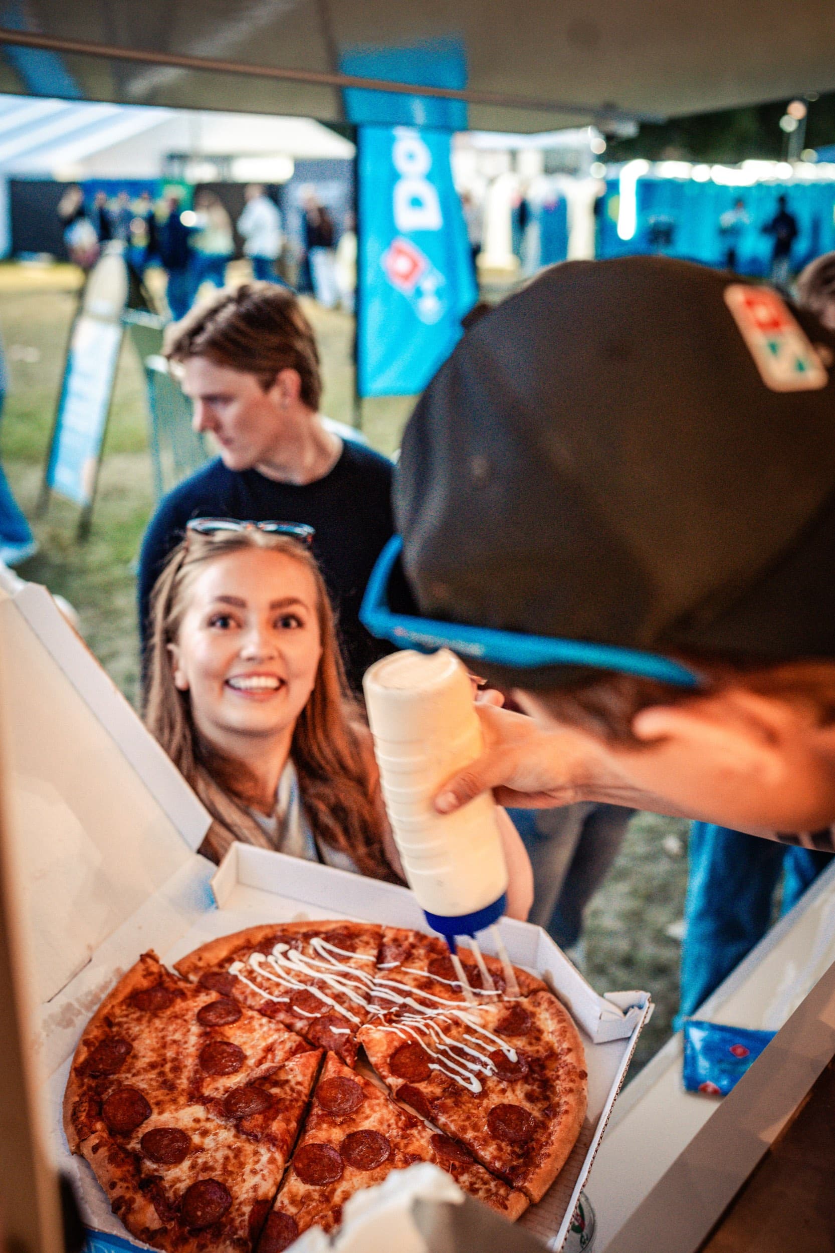 Dressing sprutes over en nylaget pepperonipizza fra Domino's