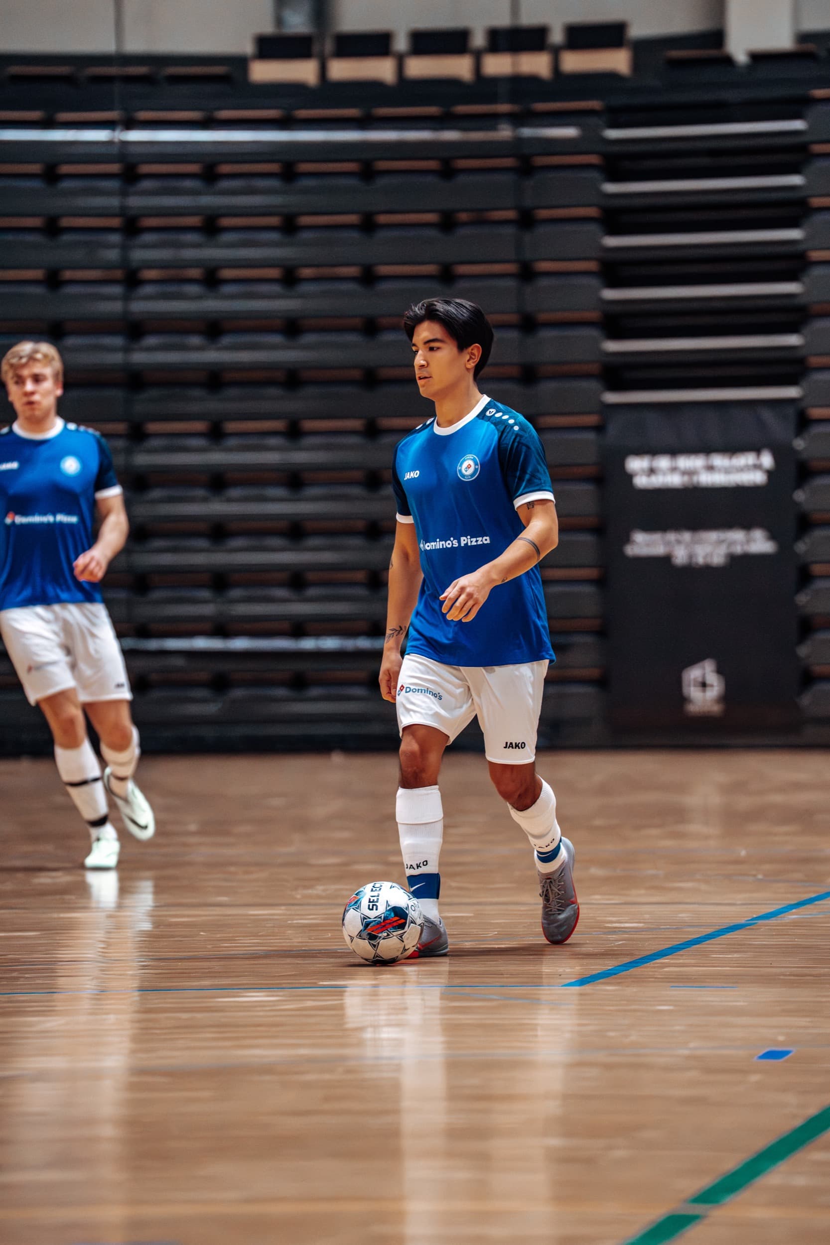 Spiller fra Domino's Elite driblet med ballen, med lagkamerat bak