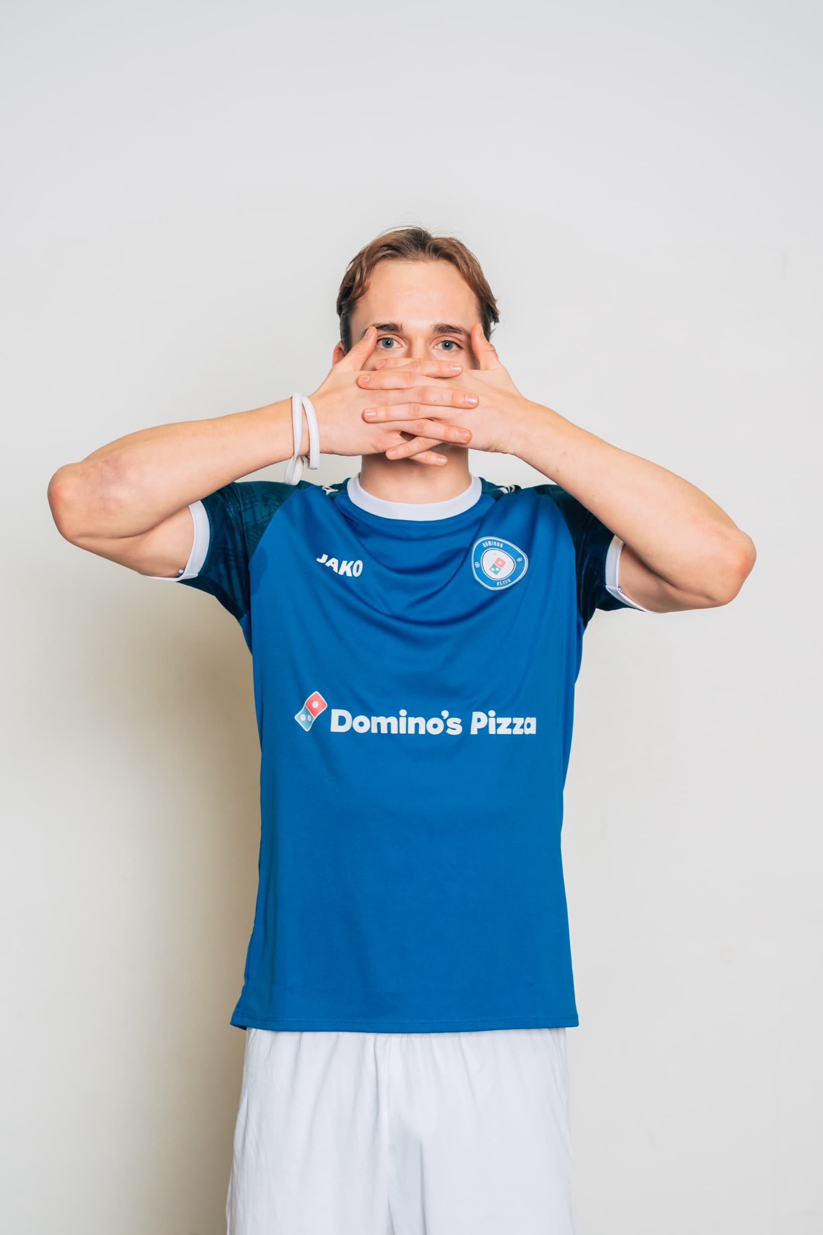 Spiller fra Domino's Elite holder hendene foran munnen i en reaksjon, med «Domino's Pizza» synlig på drakten