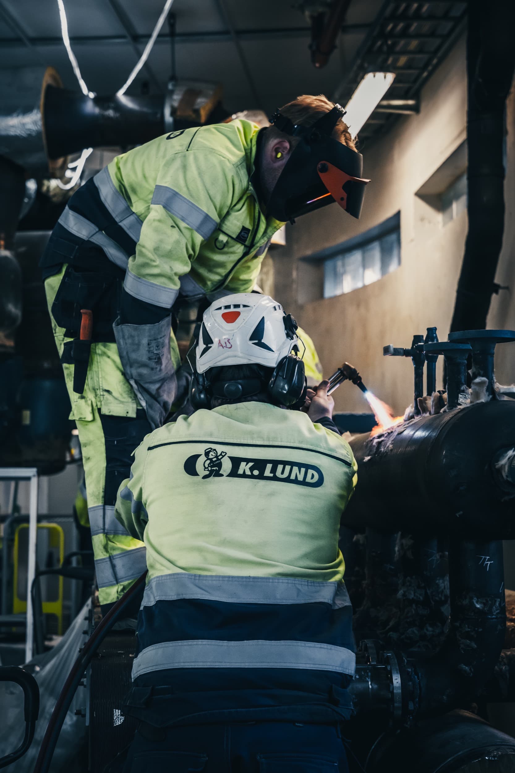 To ansatte i K. Lund samarbeider tett med en gassbrenner under arbeid
