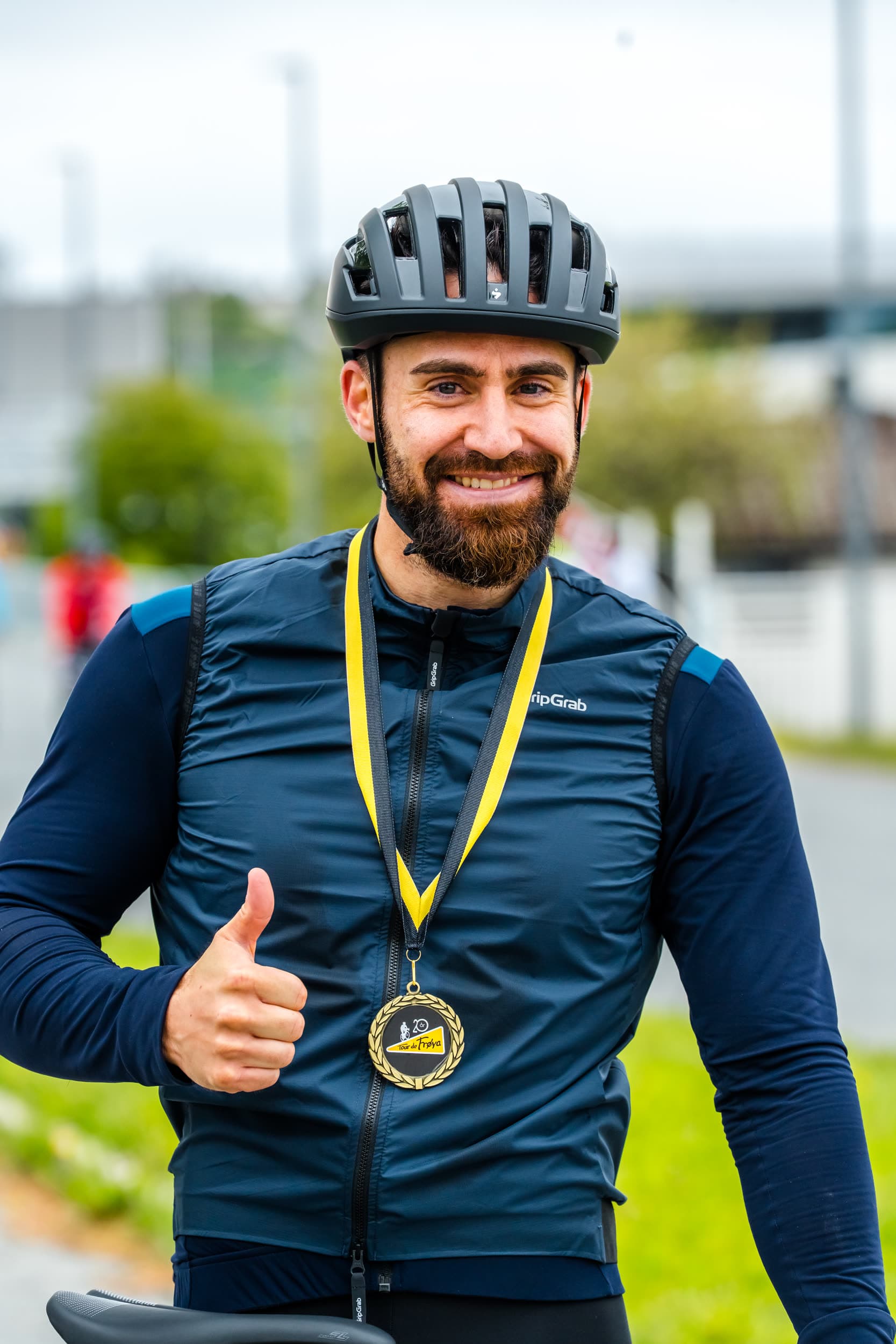 En rytter med finishmedalje rundt halsen gir tommel opp